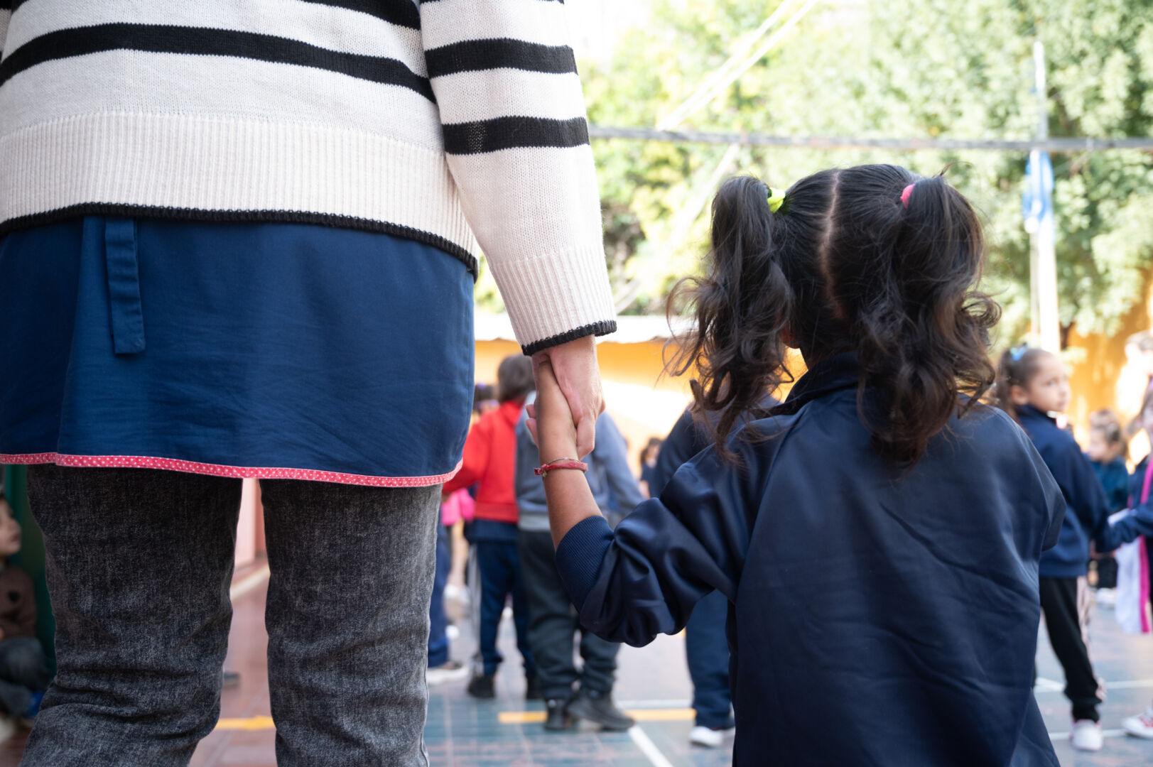 niña de la mano de una docente