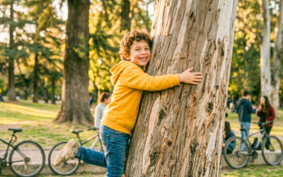 niño jugando abrazado a un árbol en un bosque